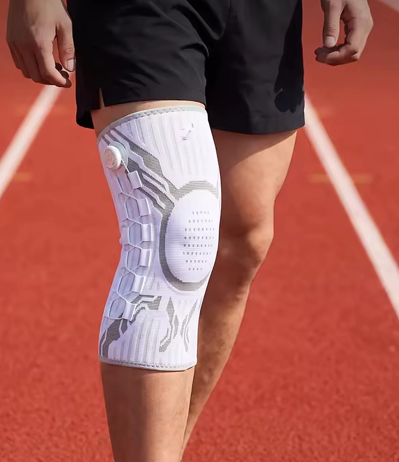 Runner wearing the light grey Fixora knee brace on a track